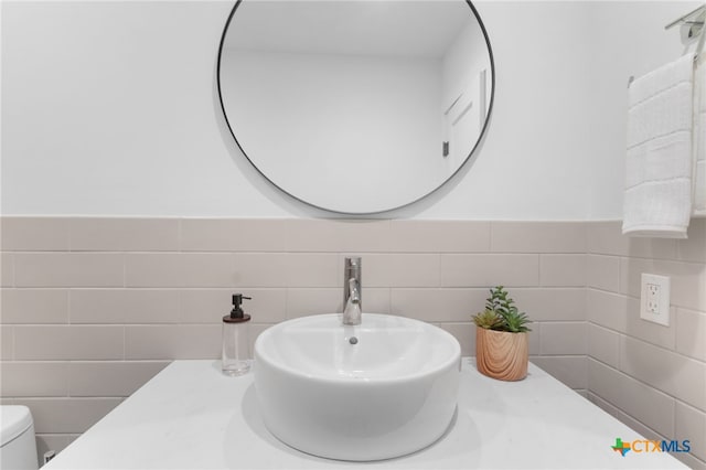 bathroom featuring toilet, tile walls, and sink