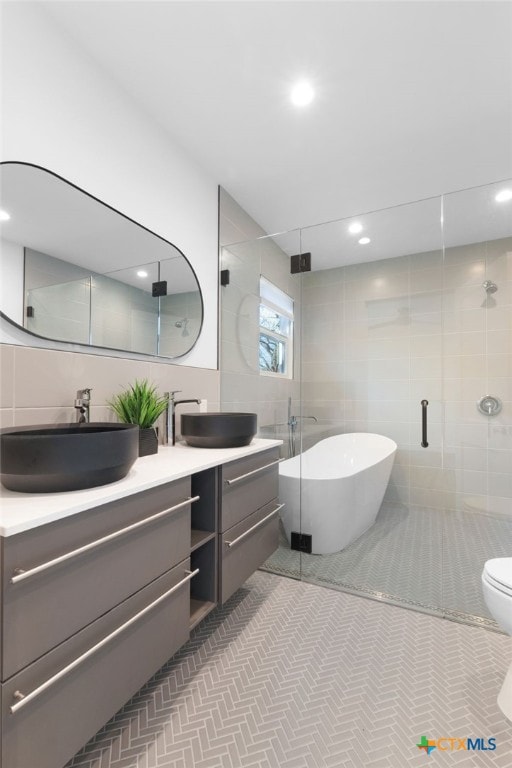 full bathroom featuring plus walk in shower, vanity, toilet, and tile walls