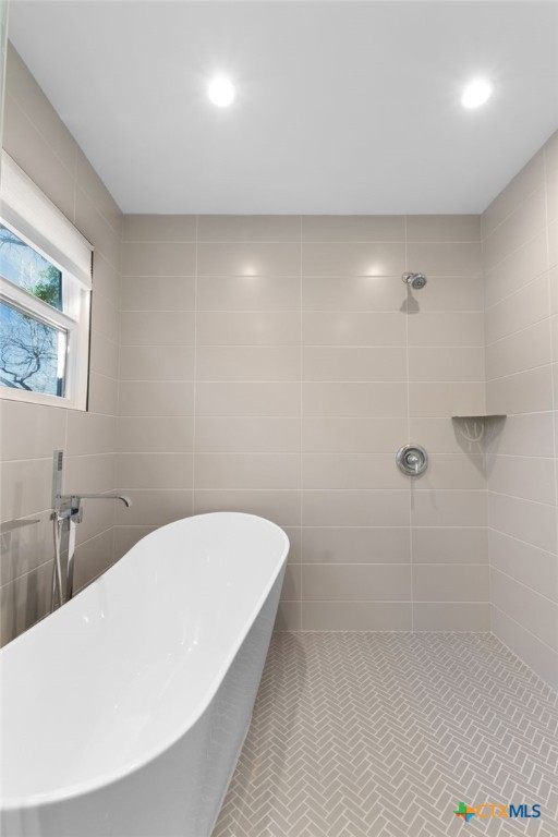 bathroom with a bathtub, tile walls, and tile patterned flooring