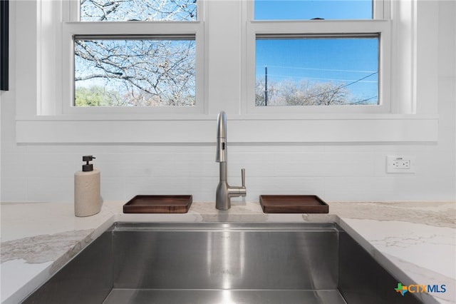 room details featuring white cabinetry, light stone counters, and sink