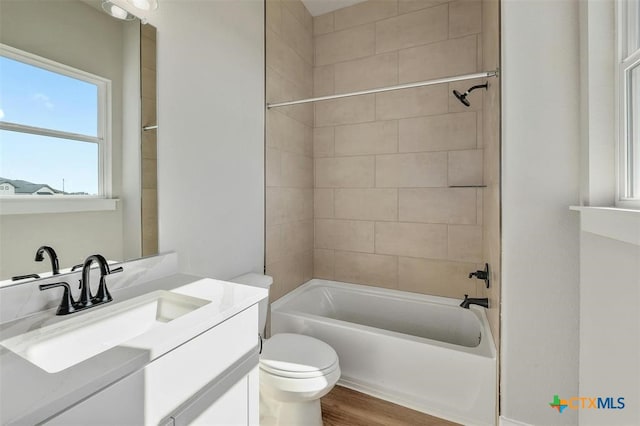 full bathroom featuring vanity, wood-type flooring, tiled shower / bath combo, and toilet