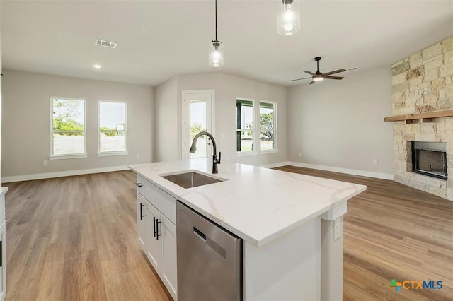 kitchen featuring white cabinetry, dishwasher, sink, light stone counters, and decorative light fixtures