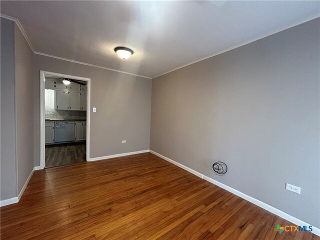 empty room with crown molding and dark hardwood / wood-style flooring