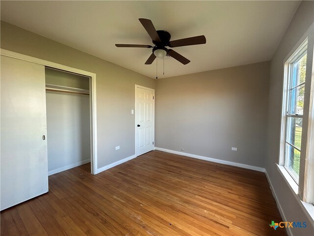 unfurnished bedroom featuring a closet, hardwood / wood-style floors, and ceiling fan