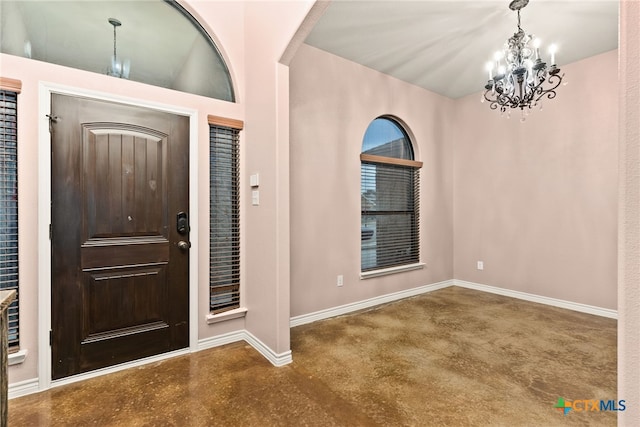 foyer with concrete flooring and a notable chandelier