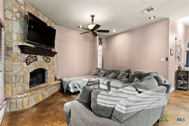 living room with a stone fireplace, concrete floors, and ceiling fan