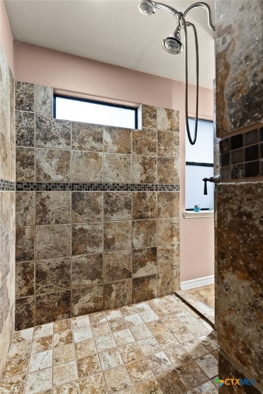 bathroom with a tile shower and a textured ceiling