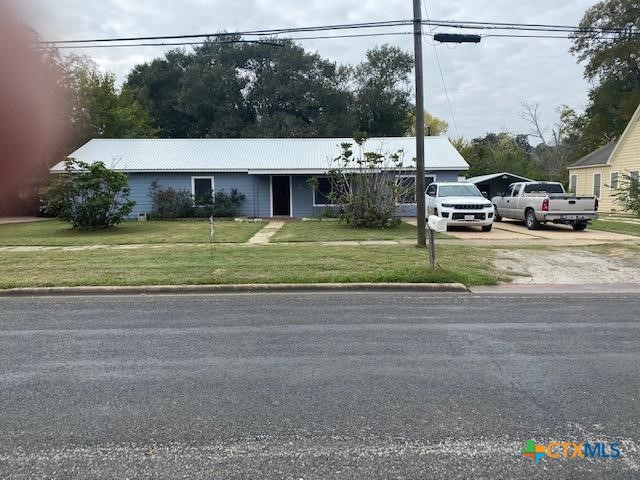 view of front of house with driveway, metal roof, and a front yard