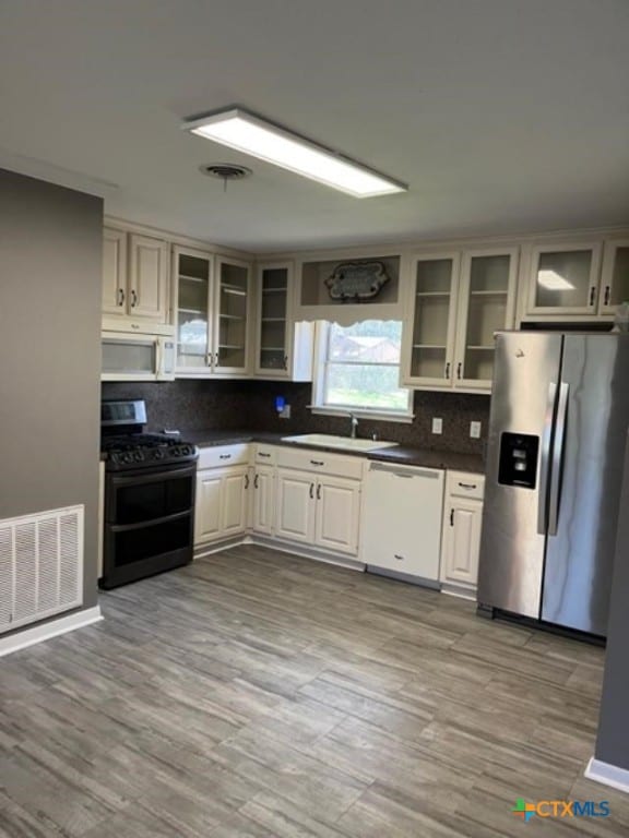 kitchen featuring white appliances, dark countertops, visible vents, and a sink
