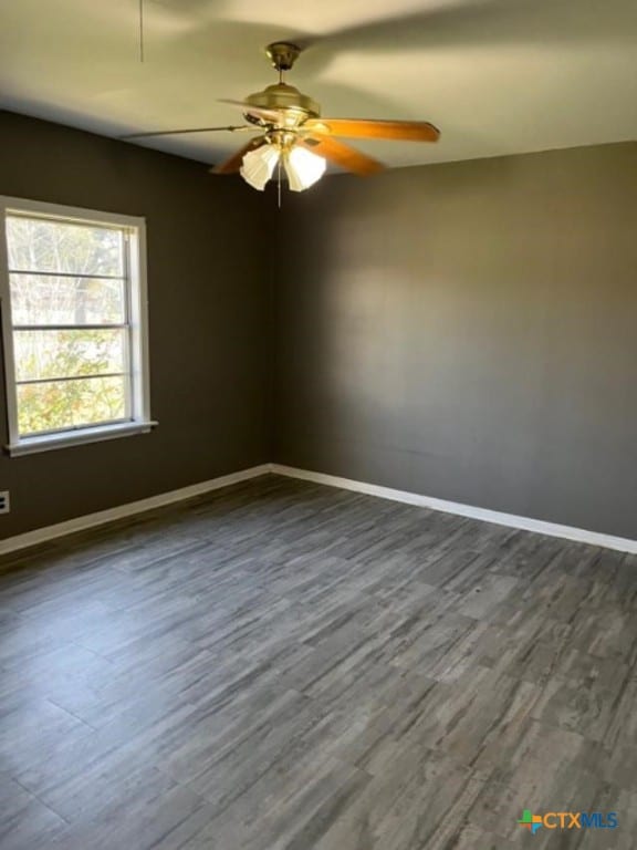 empty room with baseboards, dark wood-type flooring, and a ceiling fan