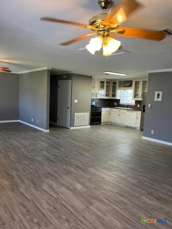 unfurnished living room featuring crown molding, baseboards, dark wood-type flooring, and ceiling fan