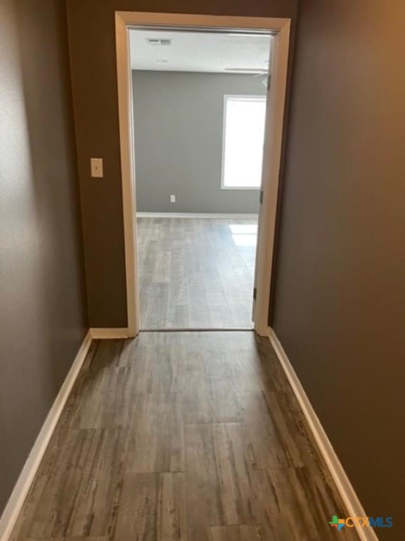 hallway with wood finished floors and baseboards
