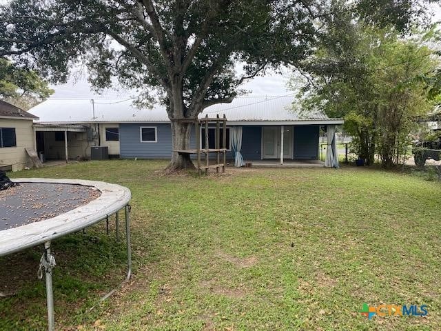 back of property featuring a lawn, central AC, and a trampoline