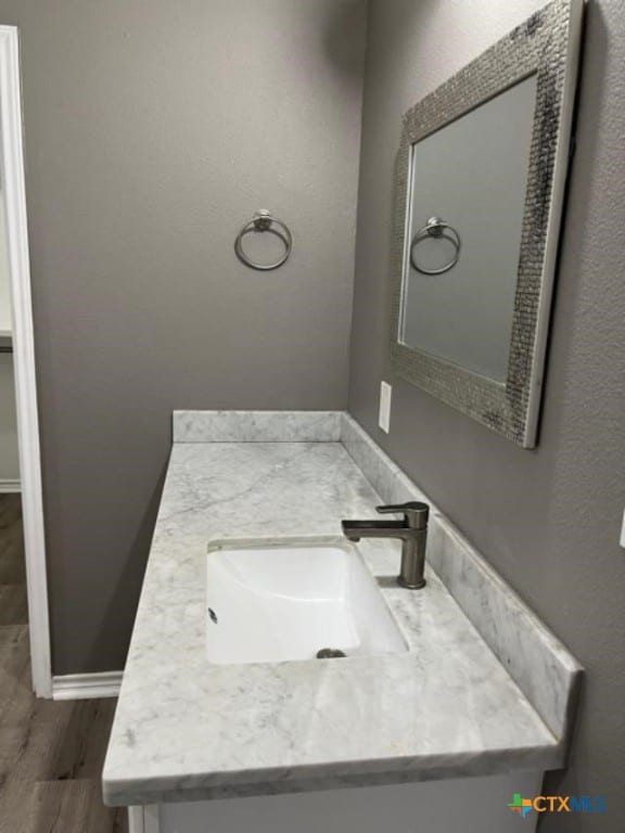 bathroom with vanity, wood finished floors, and baseboards