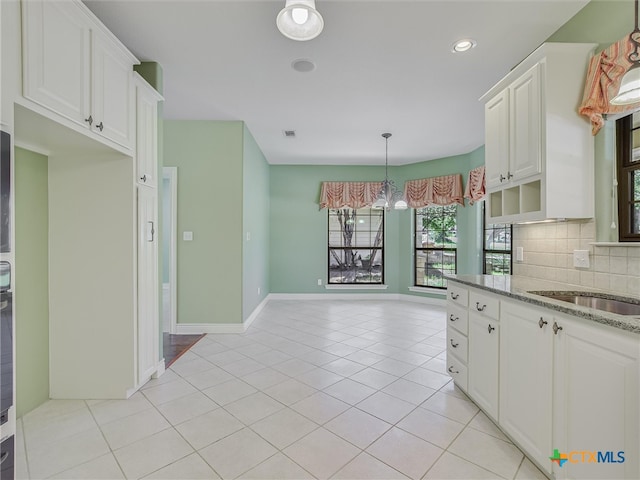 kitchen with tasteful backsplash, white cabinetry, light tile patterned floors, and light stone countertops