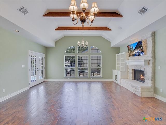 unfurnished living room with french doors, a notable chandelier, hardwood / wood-style flooring, a fireplace, and lofted ceiling with beams