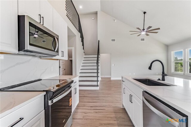 2109 Park View Dr, Marble Falls, TX 78654 - kitchen with appliances with stainless steel finishes, a sink, a ceiling fan, light wood finished floors, and white cabinetry
