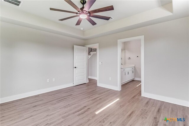 2109 Park View Dr, Marble Falls, TX 78654 - unfurnished bedroom with light wood-style floors, baseboards, a tray ceiling, connected bathroom, and a closet