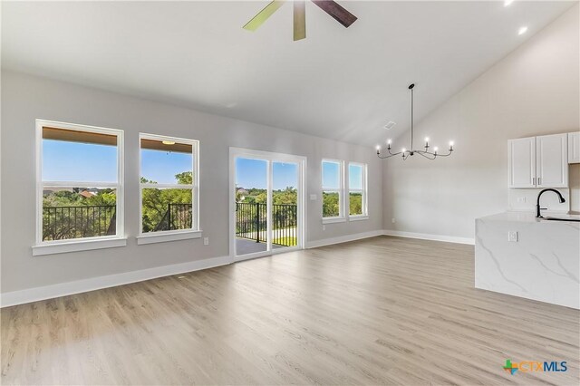 2109 Park View Dr, Marble Falls, TX 78654 - unfurnished living room featuring a chandelier, baseboards, a ceiling fan, light wood-style floors, and high vaulted ceiling