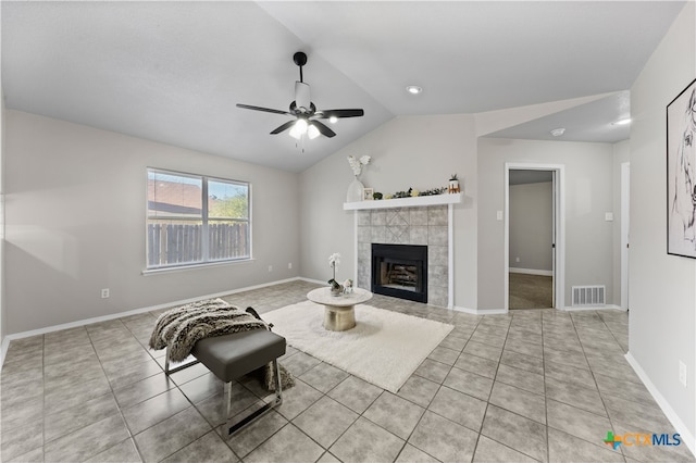 unfurnished living room with ceiling fan, a tiled fireplace, light tile patterned floors, and vaulted ceiling