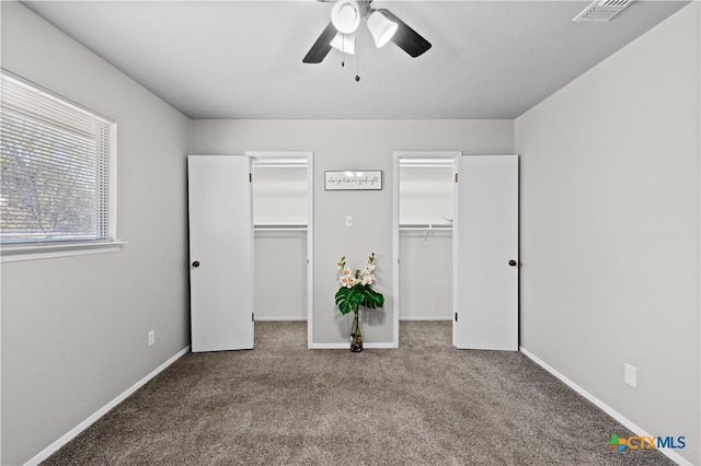 unfurnished bedroom with a walk in closet, ceiling fan, a closet, and light colored carpet