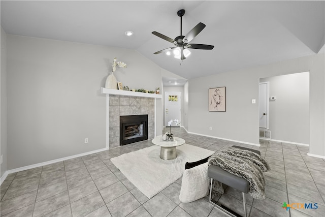 tiled living room featuring a tile fireplace, vaulted ceiling, and ceiling fan