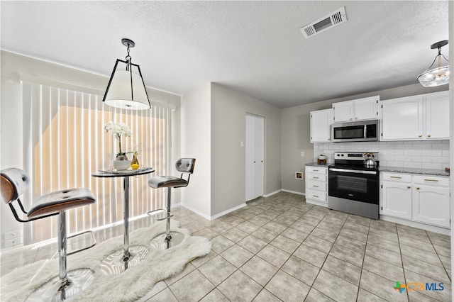 kitchen featuring decorative backsplash, appliances with stainless steel finishes, decorative light fixtures, and white cabinetry