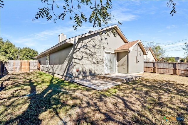 back of house with a lawn and a patio area