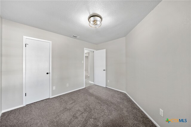 empty room with carpet flooring and a textured ceiling