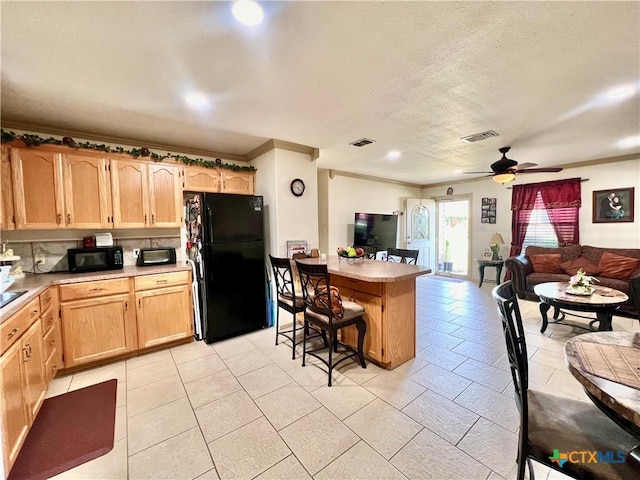 kitchen featuring black appliances, open floor plan, ornamental molding, light brown cabinets, and a peninsula