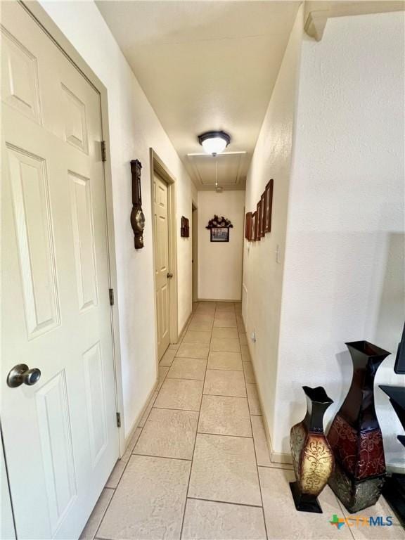 corridor with attic access and light tile patterned flooring