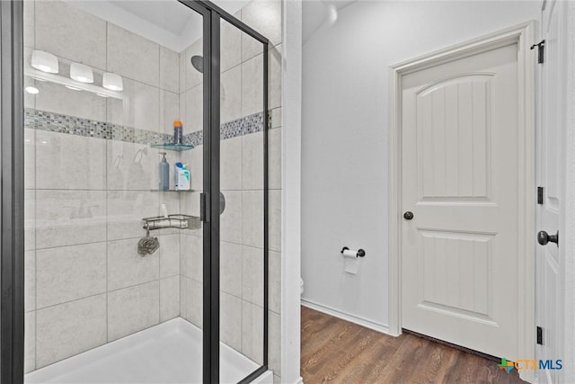 bathroom featuring a shower with shower door, hardwood / wood-style floors, and toilet