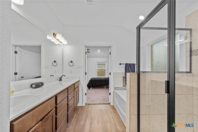 bathroom with shower with separate bathtub, wood-type flooring, vanity, and vaulted ceiling