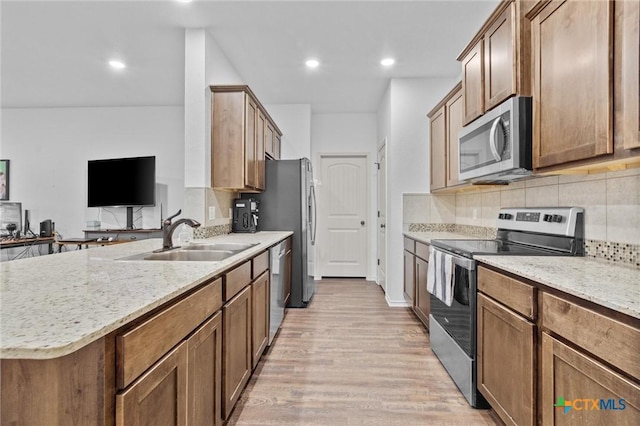 kitchen featuring light stone countertops, sink, light hardwood / wood-style flooring, and stainless steel appliances