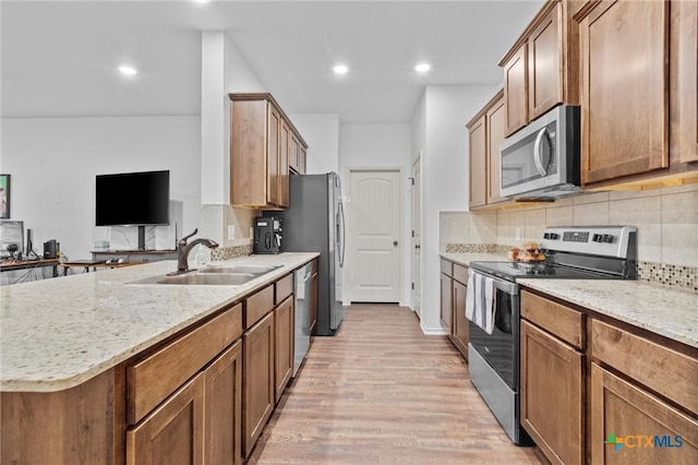 kitchen with light hardwood / wood-style floors, decorative backsplash, sink, stainless steel appliances, and light stone counters