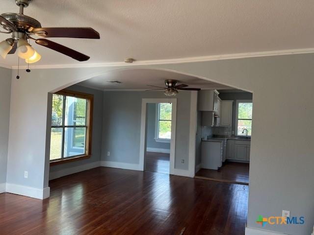 1612 Saint Peter St, Gonzales, TX 78629 - unfurnished living room with a ceiling fan, arched walkways, plenty of natural light, ornamental molding, and dark wood-style flooring