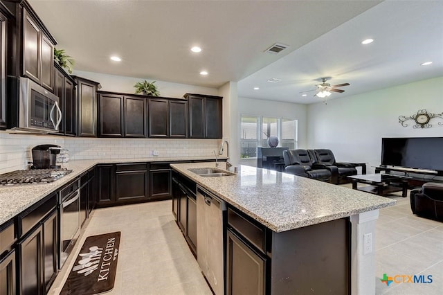 kitchen with a kitchen island with sink, stainless steel appliances, sink, and light tile patterned floors