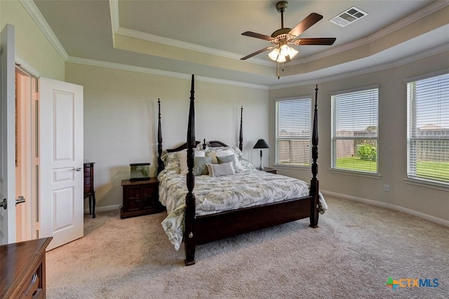 carpeted bedroom with a tray ceiling, ceiling fan, and crown molding