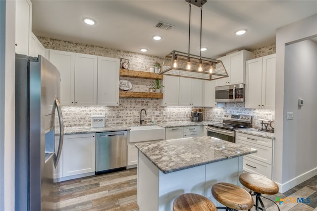 kitchen with white cabinetry, hanging light fixtures, a center island, and appliances with stainless steel finishes