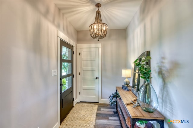 doorway with dark hardwood / wood-style flooring and a chandelier