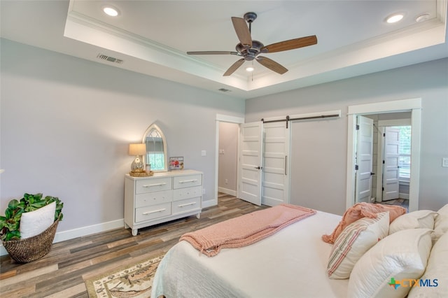 bedroom featuring dark hardwood / wood-style floors, ceiling fan, a raised ceiling, crown molding, and a barn door