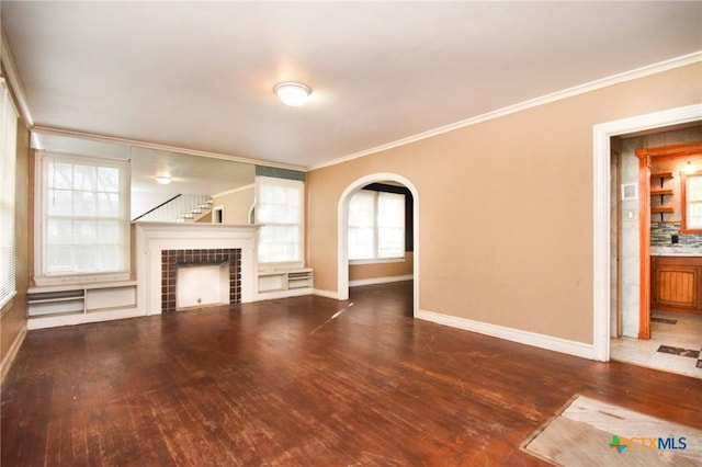 unfurnished living room featuring dark hardwood / wood-style flooring, ornamental molding, and a fireplace