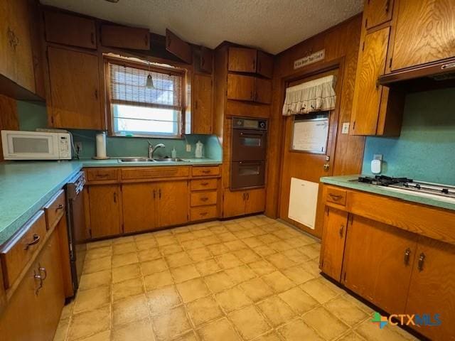 2410 Robin Rd, Temple, TX 76502 - kitchen with white microwave, gas stovetop, a textured ceiling, brown cabinets, and light countertops