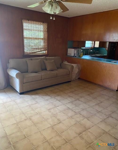 2410 Robin Rd, Temple, TX 76502 - living room featuring a ceiling fan, a textured ceiling, healthy amount of natural light, wooden walls, and light flooring