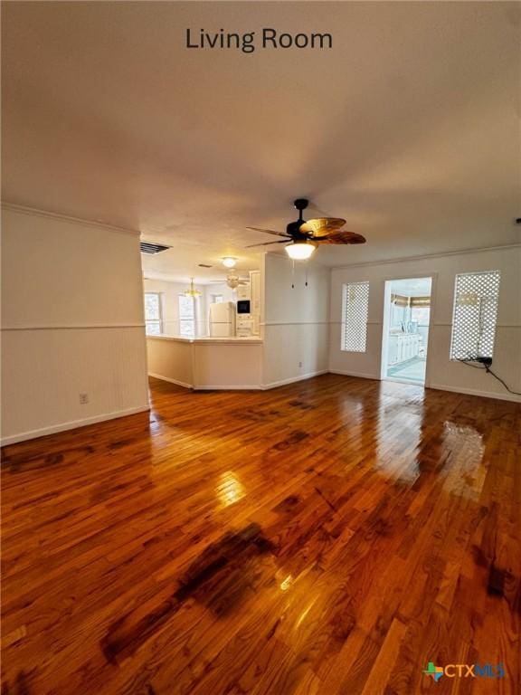 unfurnished living room with a wealth of natural light, baseboards, a ceiling fan, and wood finished floors