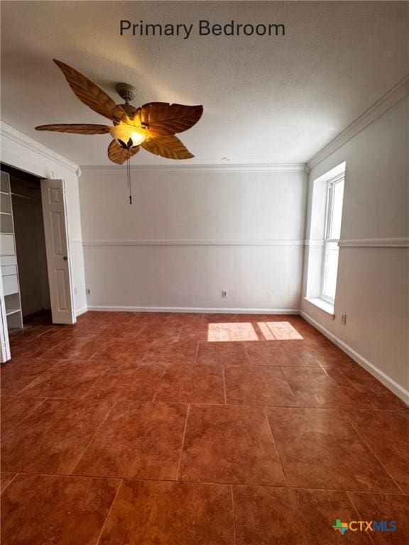 tiled empty room featuring ceiling fan, ornamental molding, and baseboards