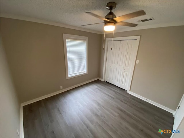 unfurnished bedroom featuring dark wood-style floors, baseboards, visible vents, and a textured ceiling