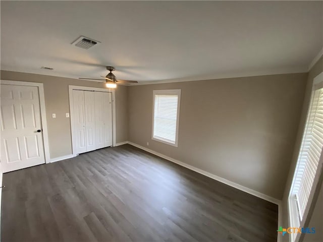 unfurnished bedroom with dark wood-style flooring, visible vents, ornamental molding, ceiling fan, and baseboards