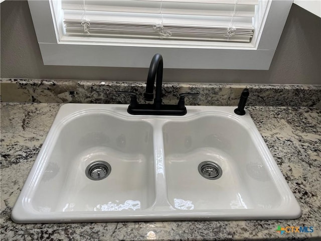 details with a textured wall, a sink, and light stone counters