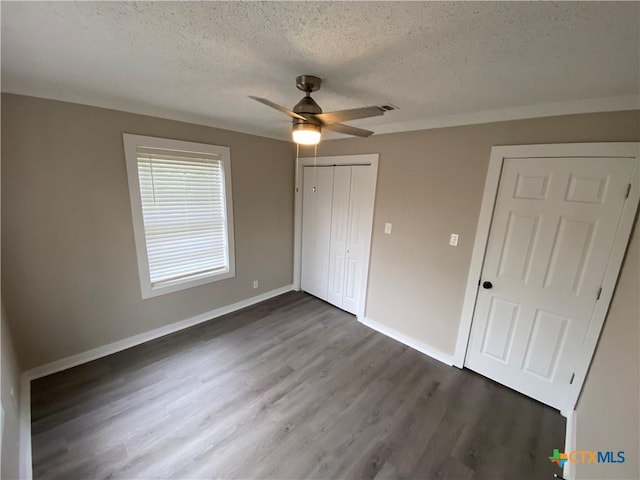 unfurnished bedroom featuring a closet, a ceiling fan, a textured ceiling, wood finished floors, and baseboards